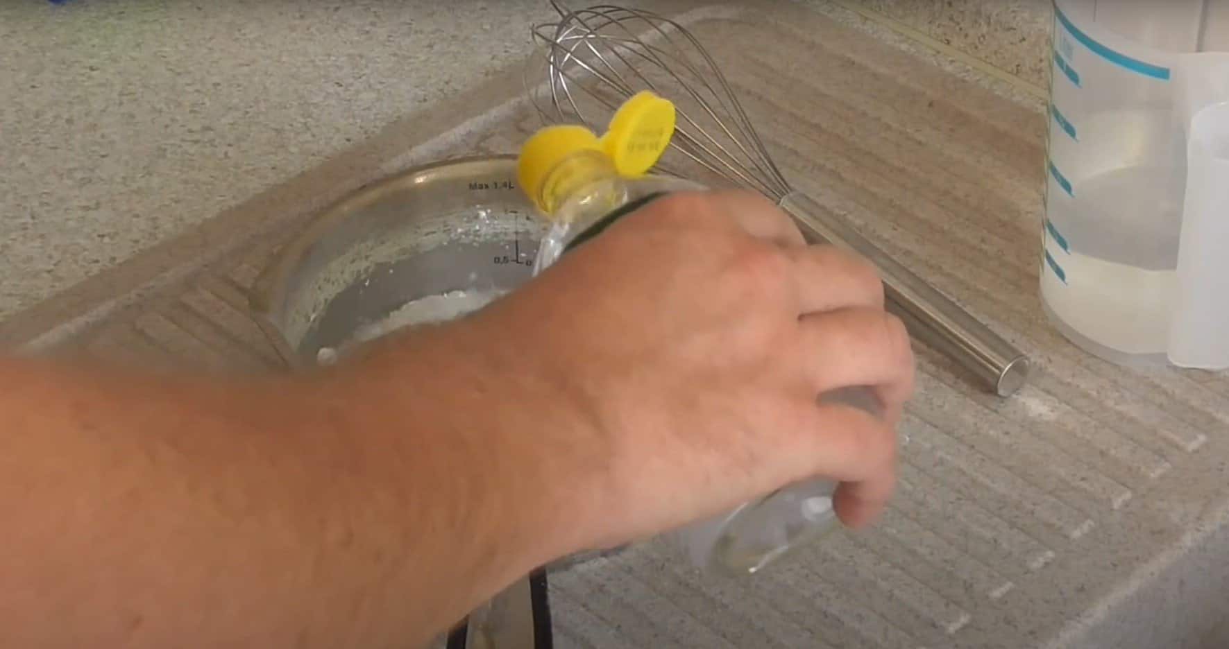 Hand gießt Essig in einen Topf mit Backpulver zur Herstellung der Reinigungslösung.